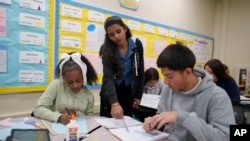 Seorang tutor membimbing para siswa dalam kegiatan belajar mengajar di Benjamin O. Davis Middle School di Compton, California, pada 6 Februari 2025. (Foto: AP/Eric Thayer)