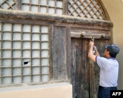 管理员给毛泽东旧居开门，左侧窗户上可以看到一个窟窿。