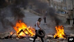 在以色列军队袭击西岸城市纳布卢斯期间,巴勒斯坦人焚烧轮胎。(2015年10月6号)