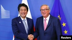 欧盟委员会主席容克在布鲁塞尔与到访的日本首相安倍晋三握手。(2019年9月27日)