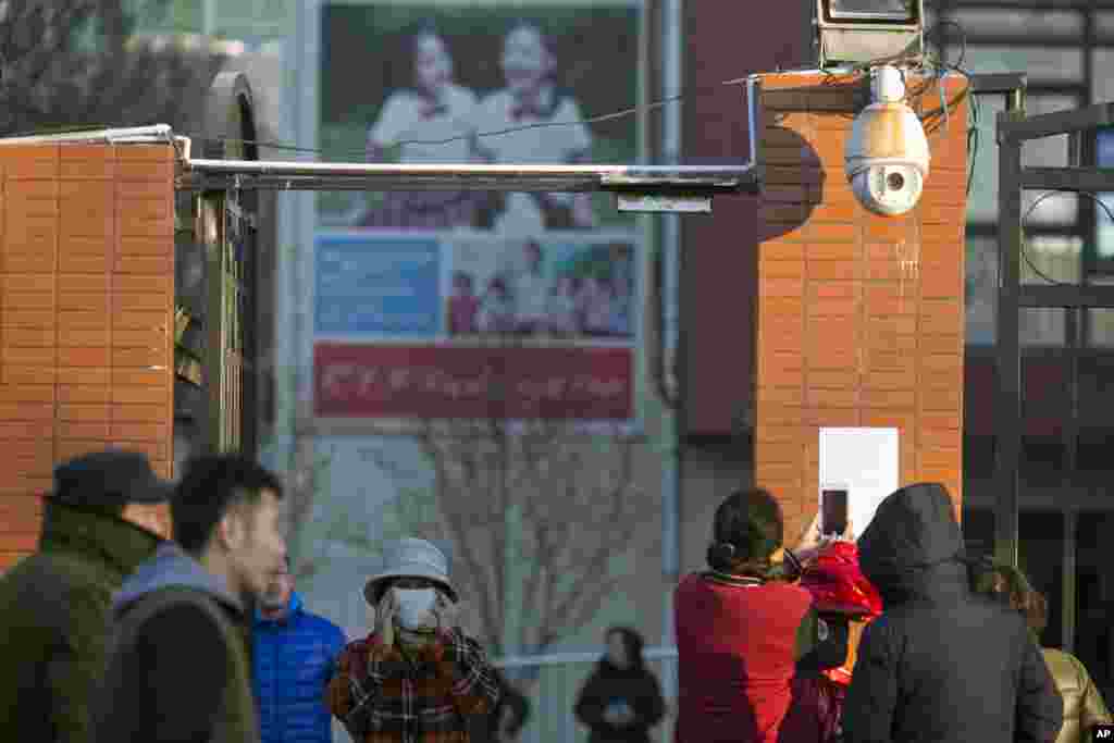 在中国北京的红黄蓝幼儿园外面,家长们观看幼儿园贴出的通知,有人拍照(2017年11月24日)。该幼儿园被举报涉嫌虐待猥亵幼儿事件持续发酵并引起社会广泛关注。朝阳区警方侦办后发现这是伤害幼儿的恶劣事件。当局责成当事企业立即将涉事幼儿园园长免职,并对该幼儿园及相关人员严肃追责。