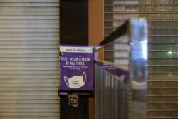 在2022年1月9日在香港采取更严格的限制措施以遏制新冠病毒的传播之后,在空荡荡的兰桂坊夜生活区的封闭酒吧外可以看到一张提醒人们戴防护口罩的海报