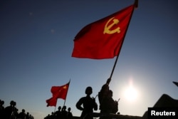 中国解放军军人在内蒙古朱日和训练基地准备参加阅兵，庆祝解放军建军90周年。中共党旗在前，国旗居中，军旗在后（2017年7月30日）