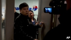 一名马航工作人员试图赶走聚集在北京国际机场马航办事处外的记者。(2014年3月8日)