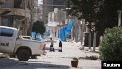 阿勒颇居民上街打水,他们在街上挂上蓝布,以防止狙击(2016年8月7日)