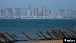 台湾金门海滩上设有防止登陆入侵的障碍物,对面就是中国厦门市的高楼。(路透社2024年2月21日)