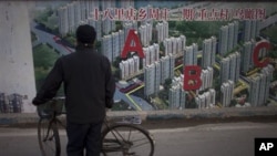 2013年1月北京一处工地旁有人观看居民楼鸟瞰图。何清涟写道,中国房地产价格攀升与全国数百座鬼城同时出现。