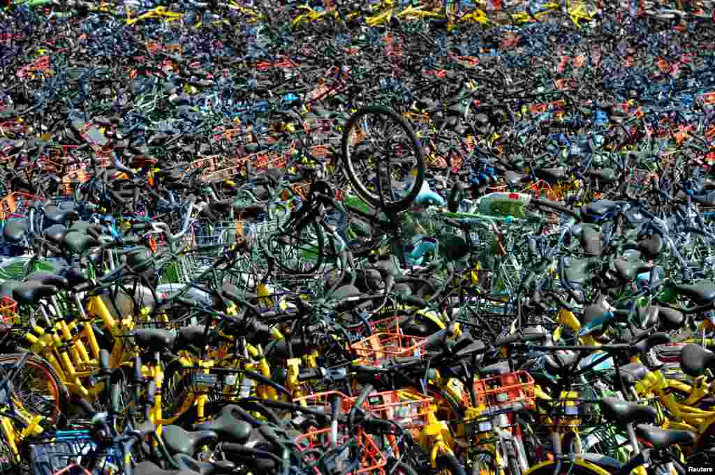 中国湖北省武汉市的一处空地上放满了各种共享自行车(2018年4月7日)。武汉共享单车有70万辆左右,部分路段投放的车辆已远超实际需求。2017年武汉发布共享单车“禁增令”。针对共享单车挤占人行道、乱停放现象,执法部门扣留违规单车,集中停放。