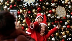 身穿圣诞老人服装的母子二人在北京一家商场的圣诞树前合影。(2017年12月25日)