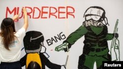 一名香港反送中抗议者在手绘一幅全副武装的蒙面港警开枪实弹射击一名抗议学生情景的壁画。(2019年10月2日)