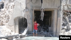 2016年7月11日,叙利亚阿勒颇老城抵抗力量占领区,一个小男孩站在遭到炸弹破坏的地方。