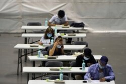 People fill out a form before receiving the Pfizer-BioNTech COVID-19 vaccine, in a vaccination center in Lyon, central France, July 7, 2021.