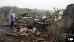 Bà Nguyễn Thị Thương, vợ của ông Đoàn Văn Vươn, đứng trước đống đổ nát của căn nhà bị chính quyền địa phương và các lực lượng vũ trang phá hủy, ngày 4/2/2012. Gia đình ông Vươn có 6 người bị truy tố và nhà cửa của họ bị phá hủy hoàn toàn.