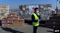 希腊雅典国际机场的一名工人站在从中国运抵的口罩等抗疫防护用品。(2020年3月21日)