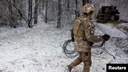 Seorang tentara Ukraina membawa satu unit Starlink di garis deopan pertempuran di Kreminna, Ukraina, pada 6 Januari 2023. (Foto: Reuters/Clodagh Kilcoyne)