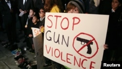 12月19日在洛杉矶市政厅前举行的烛光守夜活动中,人们举着“制止枪击暴力”的标语牌