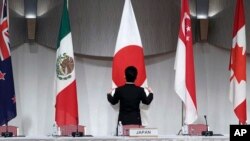 一名工作人员在东京举行的由日本主导的《跨太平洋伙伴全面进步协定》会议举行联合记者会前整理会场旗帜。(2019年1月19日)