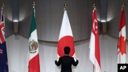 一名工作人员在东京举行的由日本主导的《跨太平洋伙伴全面进步协定》会议举行联合记者会前整理会场旗帜。(2019年1月19日) 一名工作人员在东京举行的由日本主导的《跨太平洋伙伴全面进步协定》会议举行联合记者会前整理会场旗帜。(2019年1月19日