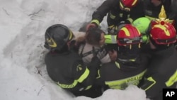 Para petugas menyelamatkan seorang perempuan dari longsoran salju di Rigopiano, Italia Januari tahun lalu (foto: ilustrasi).