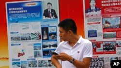 2018年8月22日,北京地铁站外的政府宣传广告牌宣传中国国家主席习近平和中国的经济成就,一名男子站在旁边。