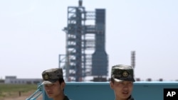 资料照:中国军人守卫在甘肃酒泉卫星发射中心的长征2F火箭和神舟十号宇宙飞船附近。(2013年6月11日)