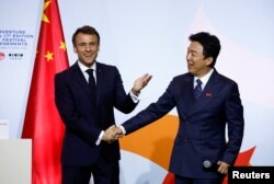 法国总统马克龙在北京向在华法国人讲话后与中国影星黄渤握手。(2023年4月5日)