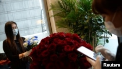 北京金融中心一家花店的工作人员带着口罩为情人节的花束订购做准备。(2020年2月14日路透社资料照)