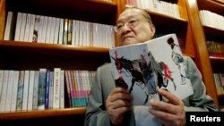 著名香港小说家、香港《明报》创办人查良镛在办公室里手持他的著作《书剑恩仇录》。(2002年7月29日)