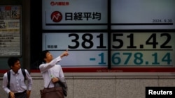 2024年9月30日,日本东京一家股票交易所外的电子屏幕显示下跌的日经平均指数。
