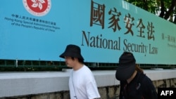 资料照:行人走过香港街头港版国安法的宣传牌。(2020年7月15日)