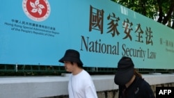行人走过香港街头港版国安法的宣传牌。（2020年7月15日）