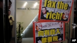 人们在莫萨克·冯赛卡律师事务所的香港地区总部附近示威,举着的标语牌上有英国首相卡梅伦和中国主席习近平的像(2016年4月12日)