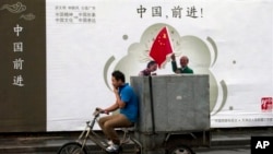 2013年7月15日北京送货自行车驶过宣传广告牌“中国,前进!”