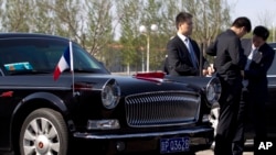 在北京首都机场,警卫人员守卫在一辆准备迎接法国总统奥朗德的红旗牌轿车旁。(2013年4月25日资料照)