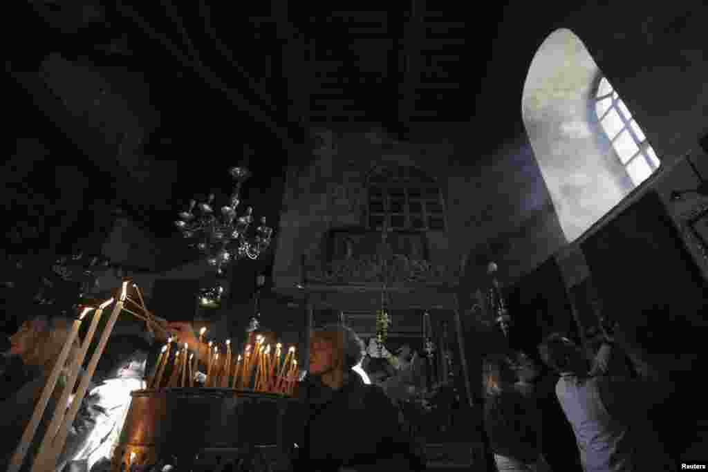 Visitors light candles in the Church of the Nativity ahead of Christmas in the West Bank town of Bethlehem, Dec. 23, 2013.