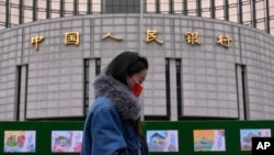 资料照:一名女子走过位于北京的中国人民银行。(2024年2月20日)