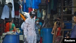 在孟买一处贫民窟,工作人员戴着智能温度扫描头盔在远距离检查人们的体温。 (2020年7月23日)