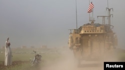 一名叙利亚男子在靠近土耳其边界处向经过的美军车辆招手(2017年4月28日)