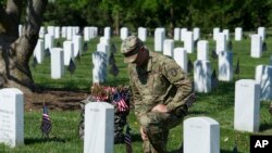 在华盛顿郊区的阿灵顿国家公墓,号称老卫队的美国陆军第三步兵团的一位军人把小型国旗插在每一座墓碑前,他短暂停下来,悼念一名阵亡者(2018年5月24日)。
