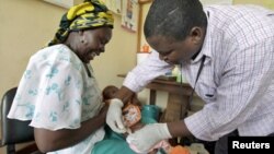 Một bà mẹ người Kenya đưa con đi chích ngừa sốt rét trong chương trình thử nghiệm