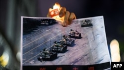 资料照：在香港维多利亚公园参加纪念六四事件31周年的一名男子手持天安门广场“坦克人”的照片。（2020年6月4日）