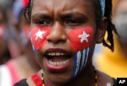 Seorang mahasiswa Papua dengan wajah dicat bendera "Bintang Kejora" meneriakkan slogan-slogan dalam unjuk rasa di depan Istana Kepresidenan di Jakarta, 28 Agustus 2019. (Foto: AP/Tatan Syuflana)