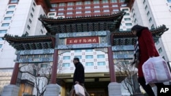 资料照片:居民从北京王府半岛酒店门前经过。(2018年11月16日)