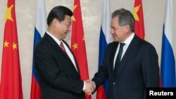 资料照:中国领导人习近平在访问莫斯科期间与时任俄罗斯国防部长、现任俄罗斯联邦安全会议秘书、前国防部长谢尔盖·绍伊古(Sergei Shoigu)(右)握手。(2013年3月23日)