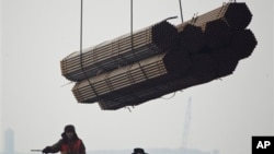 在中国唐山曹妃甸港口,工人把钢管装船。(2012年2月20日)中国钢铁业产能严重过剩