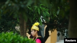 2021年4月13日,一名身着维吾尔族服装的女子站在广西钦州环球电子股份有限公司的厂区内(路透社)。