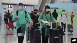 身穿防护服和戴口罩的旅客抵达香港国际机场。(2020年3月23日)