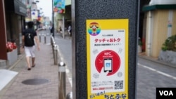 东京路边灯柱上贴着带二维条码的广告,写着“触一下,有便宜拿”