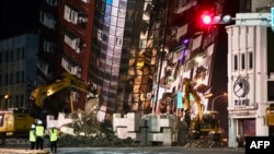 台湾花莲,救援人员站在一栋严重倾斜的大楼前。(2024年4月3日)