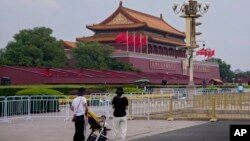 带着孩子的妇女站在北京天安门广场为中共建党100周年的纪念活动做准备而竖起的路障前。(2021年6月23日)